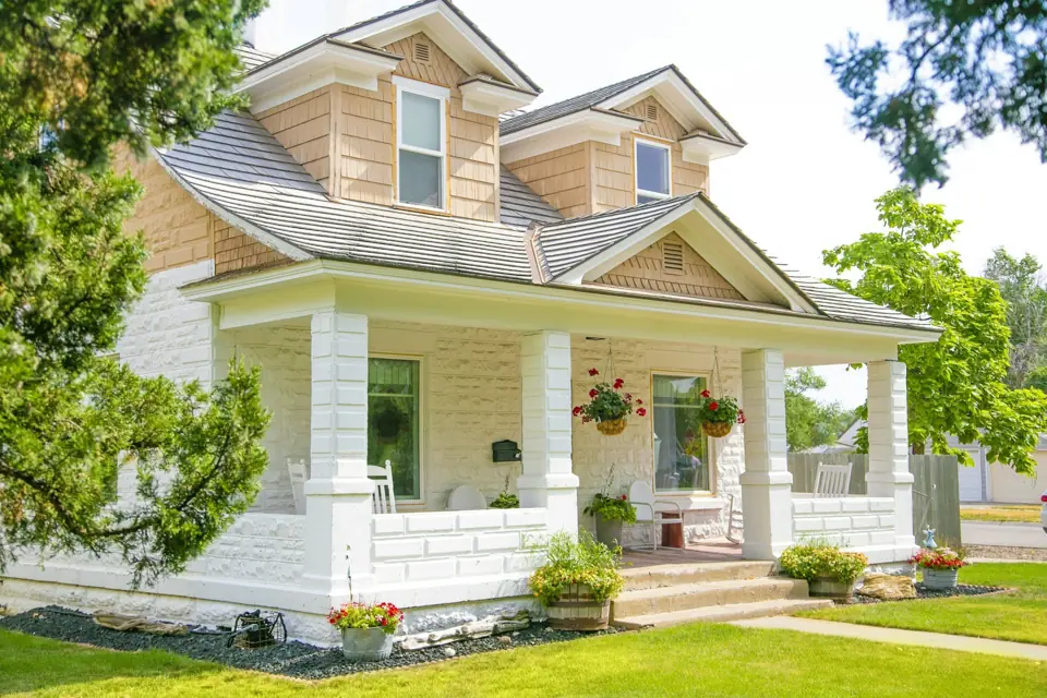 Craftsman house with a covered front porch, stone base and white columns