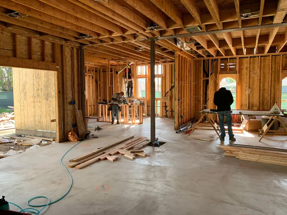 Interior of a wood-framed structure under construction with lumber on the slab