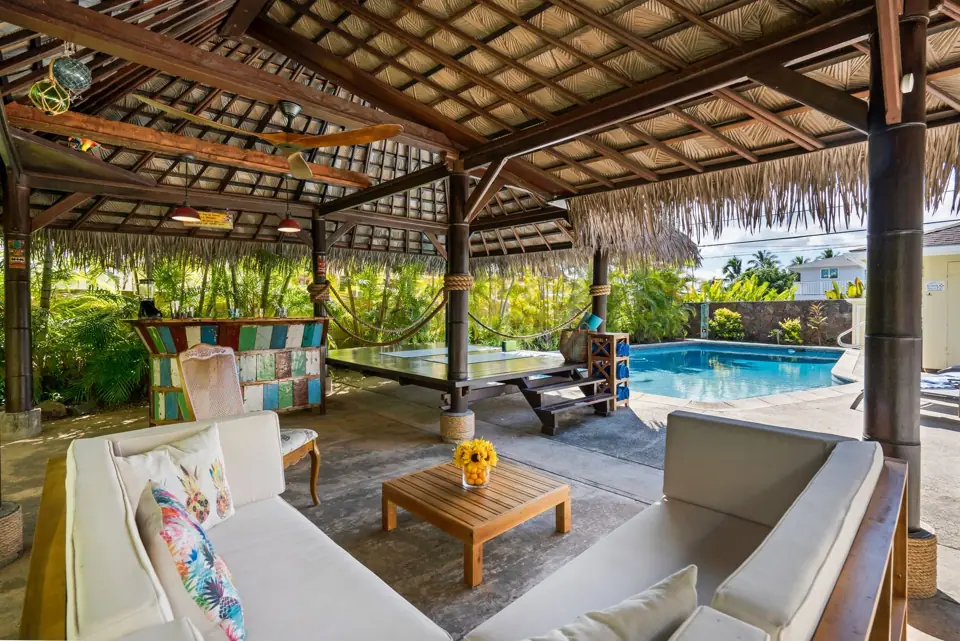 Covered outdoor pavilion with seating beside a pool