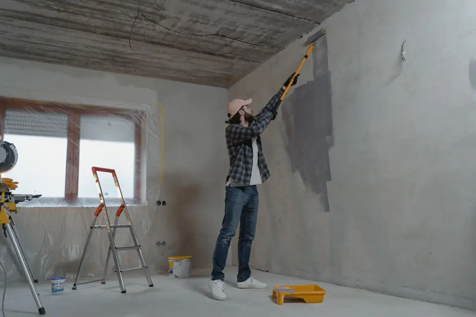 Painter rolling gray paint onto an interior wall