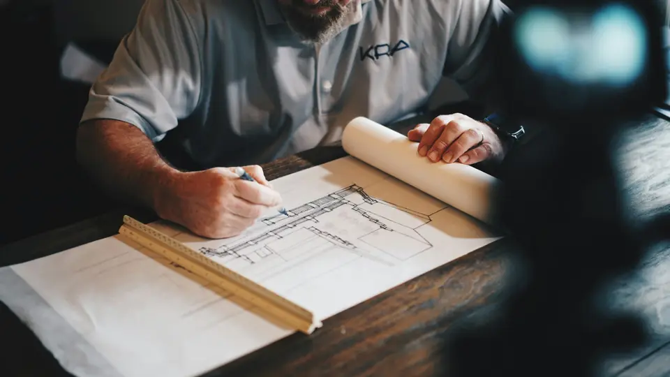 Builder drawing on construction plans at a table