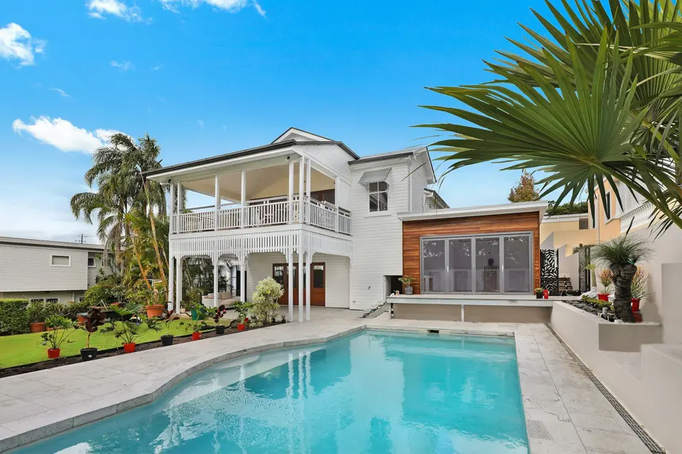 White two-story house with a covered patio and a pool in the backyard