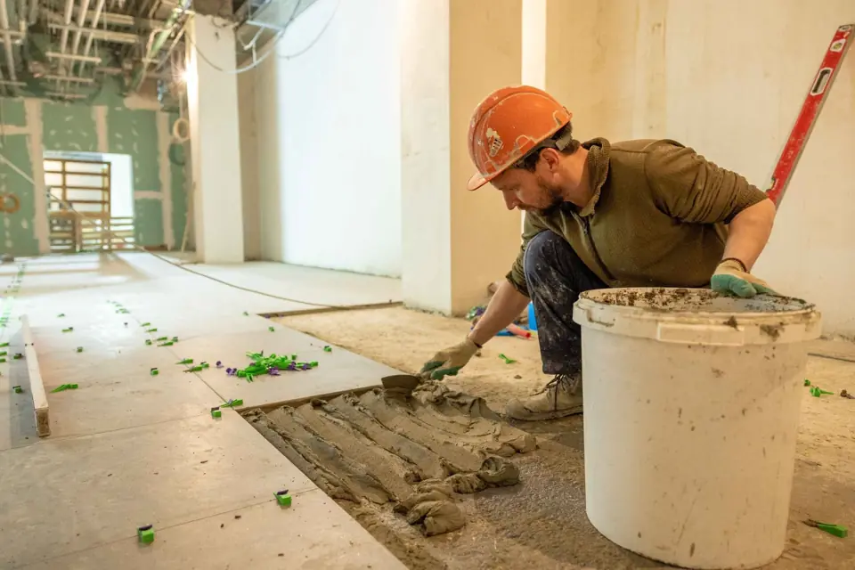 Tile setter spreading mortar on a floor during a renovation